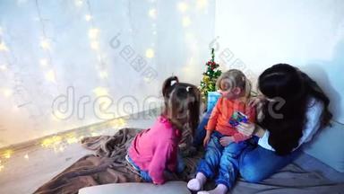 美丽的姐姐，在<strong>圣诞树和圣诞树</strong>的背景下，<strong>和</strong>坐在地毯上的小<strong>女孩</strong>玩耍
